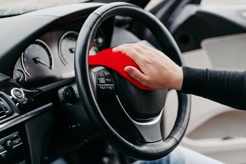 pessoa-com-um-pano-vermelho-a-limpar-o-volante-preto-de-um-carro-1