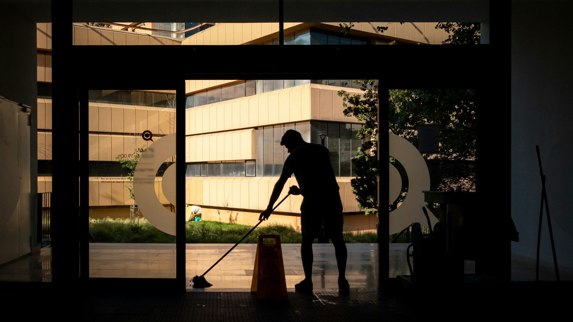 Funcionário a limpar a entrada de um prédio